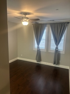 a living room with a ceiling fan and windows with curtains